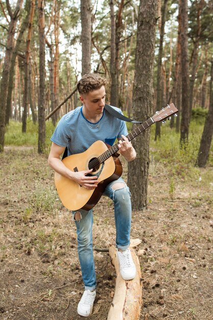 artist playing guitar in forest. bard hiking and traveller lifestyle