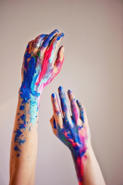 Photo the artist's hand with a thin brush dipped bright fluorescent acrylic paintsblue pink turquoise the concept of creativity inspiration