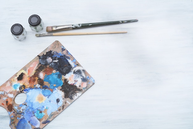 Artist's palette with colorful oil paint strokes and paintbrushes 