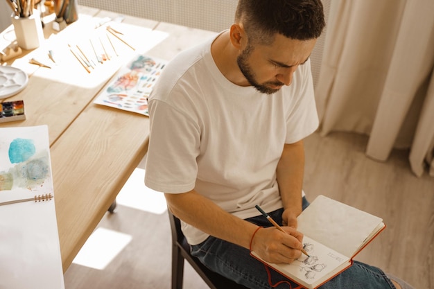 The artist sits on a chair and makes a sketch Top view of the artist's desktop in the studio Creative workshop lifestyle the process of creating a work of art