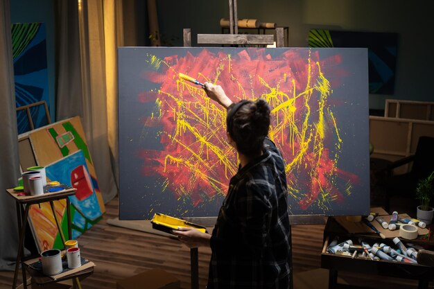 The artist spends time in the studio painting an abstract painting in tones of yellow and red