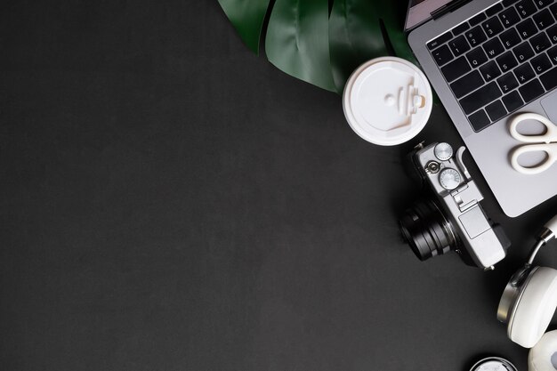 Photo artist table computer, camera, coffee and headphones on black table with top view