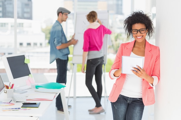 Artist using digital tablet with colleagues in background at office