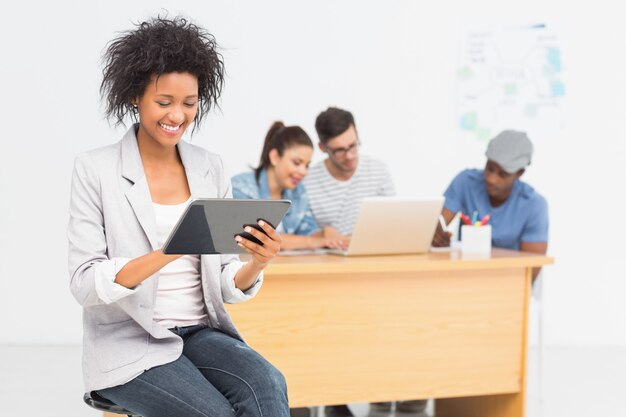 Artist using digital tablet with colleagues in background at office