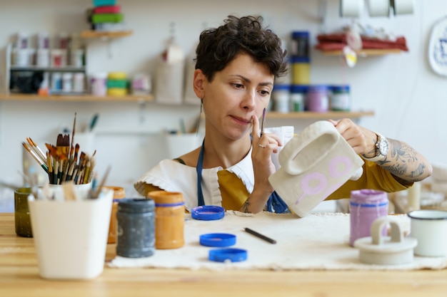 Foto artista donna pittura ceramica terracotta piccolo proprietario di studio di ceramica fare brocca di vasaio fatta a mano per la vendita