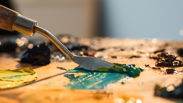 Foto lavoro dell'artista arte della pittura mestiere professionale spatola che mescola i colori blu giallo nero olio o vernice acrilica su una vecchia tavolozza di legno macchiata