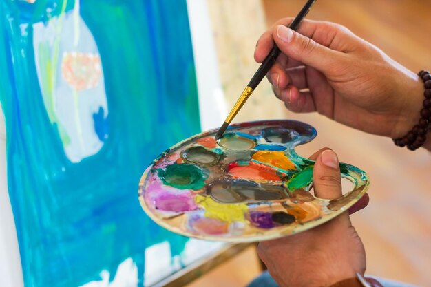 Artist at work in a studio artist with black medical mask painting picture