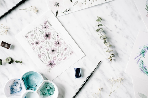 Artist workspace. Watercolor paintings with frames and flowers