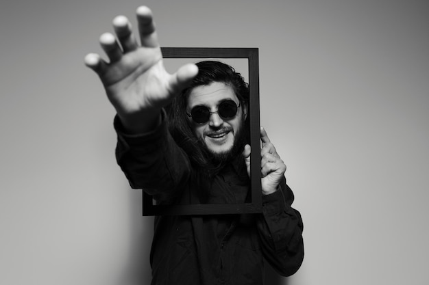 Artistic portrait of young handsome man pulling out his hand through frame