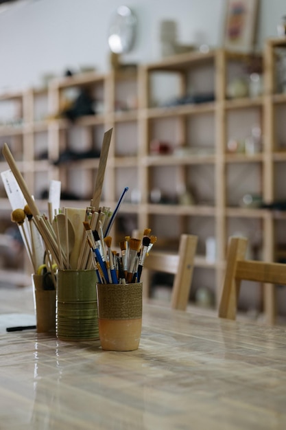 Photo artistic pottery studio interior with ceramic tools and brushes on a work table