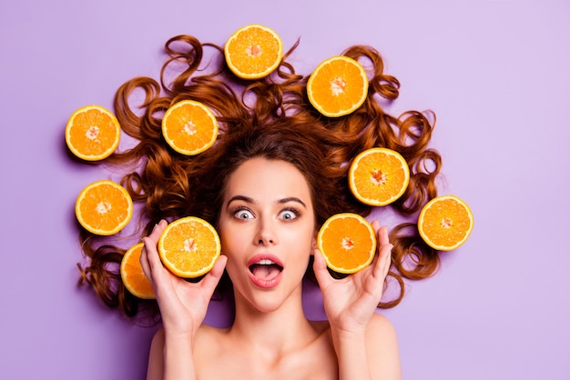 Artistic redhead woman posing with oranges in her hair