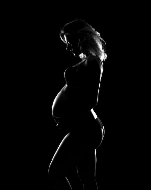 Siluetta artistica della donna incinta bionda su fondo isolato