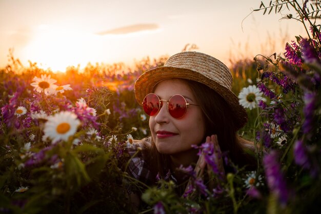 Artistiek portret van vrouw in rode bril tussen bloemen