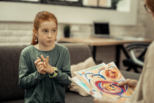 Artistieke expressie. aangename, attente meid die over haar schilderij praat tijdens een sessie met professionele psycholoog