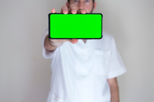 Arts achter een mobiele telefoon met het groene scherm.