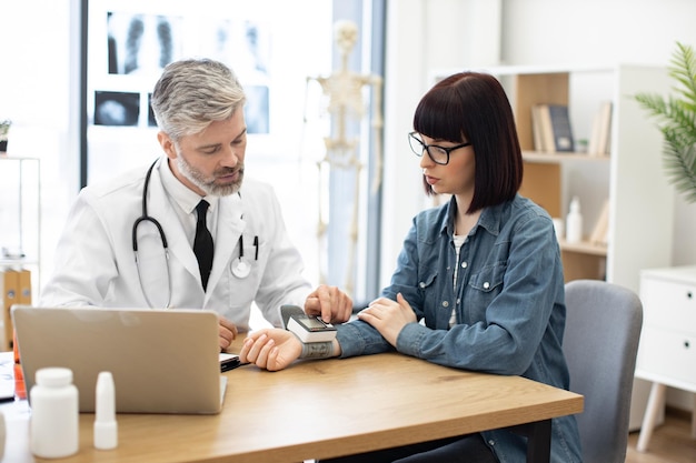 Arts die de hartslag van een vrouw meet met een draagbare tonometer