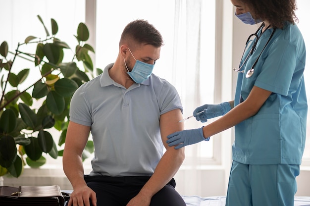 Foto arts die een patiënt in een kliniek vaccineert