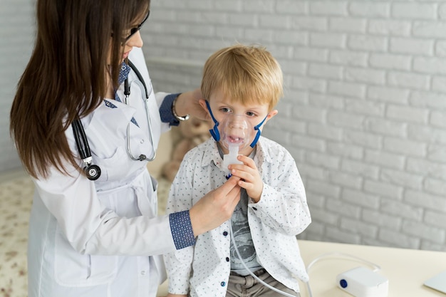 Arts die medicijninhalatiebehandeling toepast op een kleine jongen met astma-inhalatie