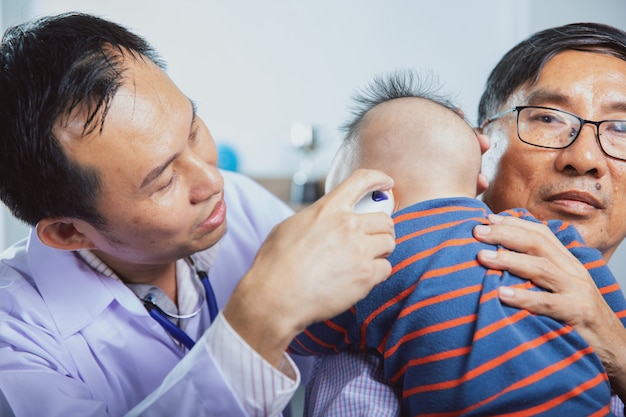 Arts die otoscoopinstrument gebruikt om het oor van de baby in het ziekenhuis te controleren