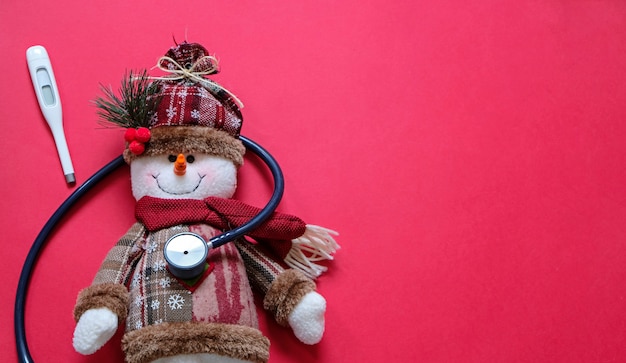 Arts en Kerstmis concept. Zieke sneeuwman en stethoscoop op rood