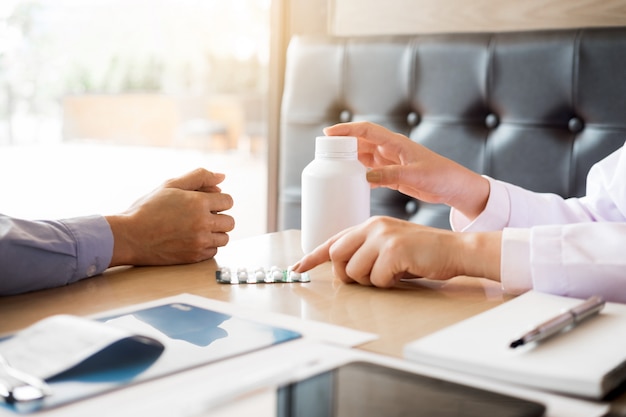 arts hand met tablet van drugs en uit te leggen aan de patiënt in het ziekenhuis kamer.