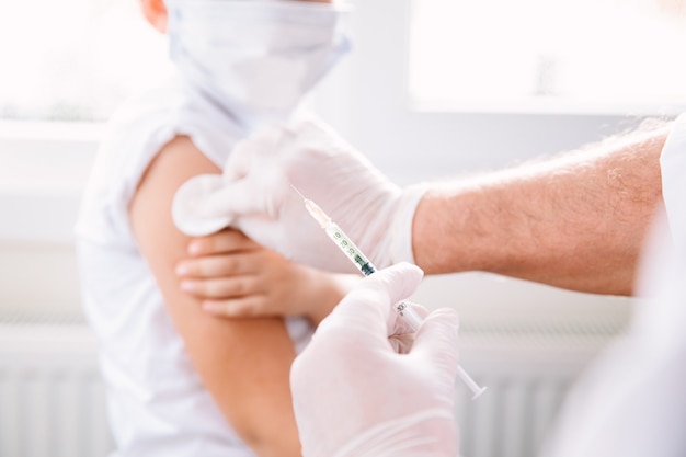 Arts in beschermende handschoenen en medisch masker injectiespuit vullen met covid-19-vaccin.