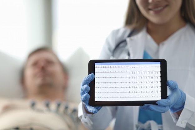 Arts in de kliniek toont patiënten cardiogram tablet