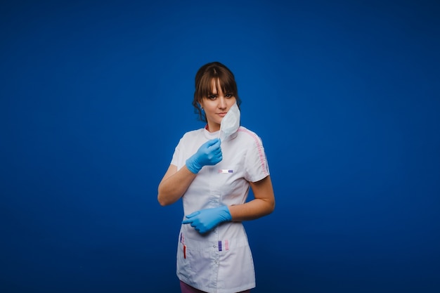 arts in een beschermend masker en rubberen handschoenen op een blauwe achtergrond