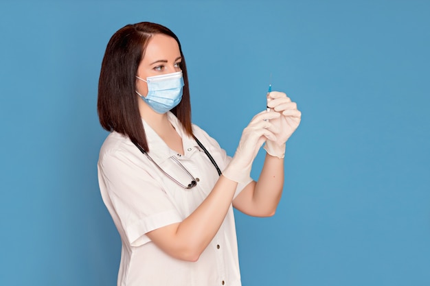 arts in een witte jas in een medisch masker en handschoenen heeft een injectiespuit. Gezondheidszorg concept