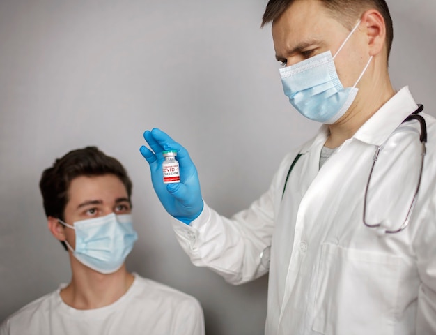 Arts in medisch masker en handschoenen die ampul en spuit met coronavirusvaccin houden