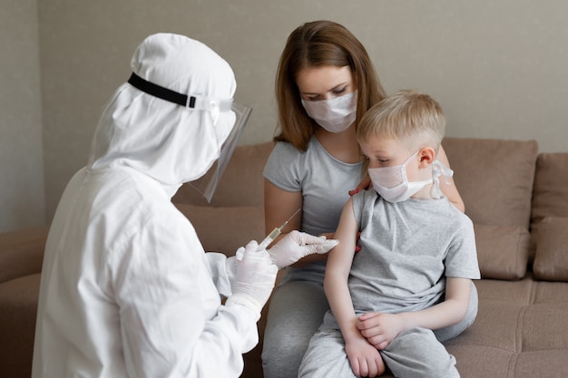 Arts in persoonlijk beschermend pak of PPE injecteert vaccinschot