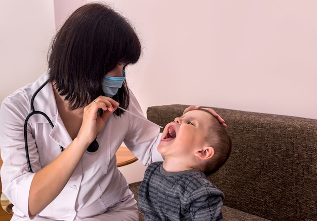 Arts kinderarts onderzoekt keel van kleine jongen