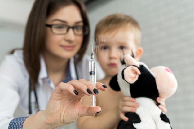 Arts kinderarts speelt voor de injectie met de jongen.