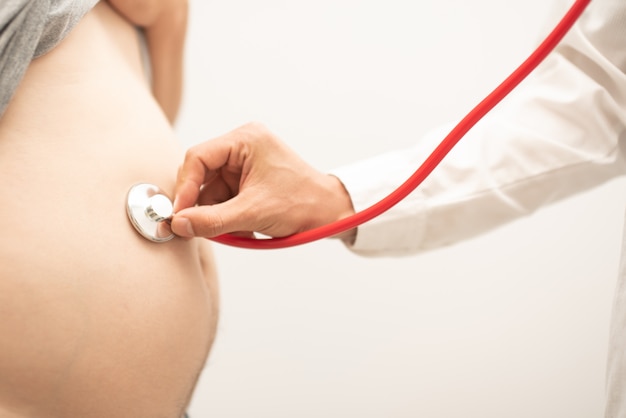Arts met behulp van stethoscoop luisteren baby in zwangere vrouw voor het controleren van hartslag van baby