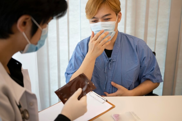 Arts met beschermend masker die het behandelplan aan zijn patiënt uitlegt