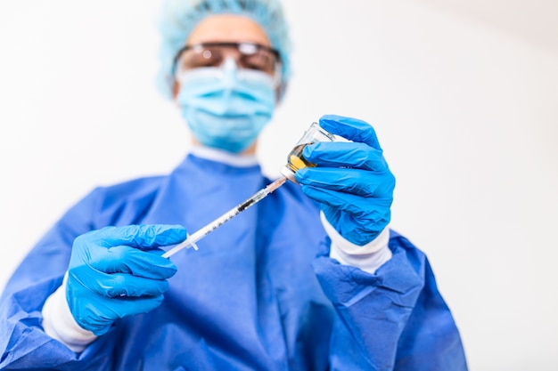 Arts of wetenschapper in ppe-suite uniform medicijn vloeibaar vaccin te houden