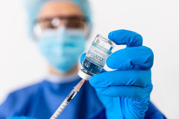 Arts of wetenschapper in PPE-suite uniform medicijn vloeibaar vaccin te houden