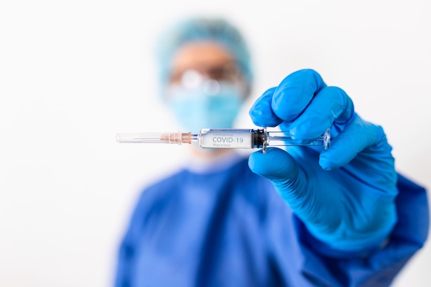 Arts of wetenschapper in PPE-suite uniform medicijn vloeibaar vaccin te houden