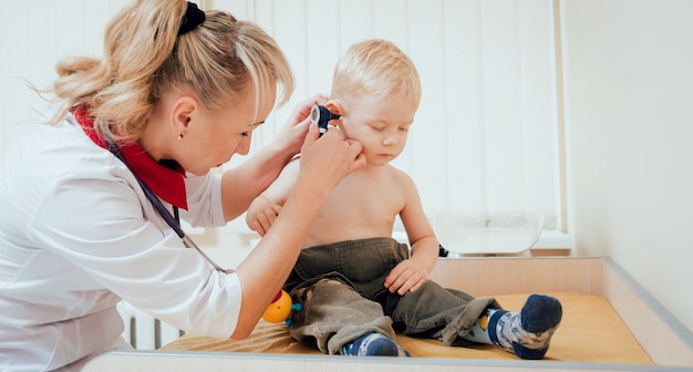 Arts onderzoekt oor met otoscoop in een kinderarts kamer.