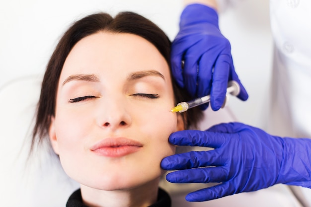 Arts-schoonheidsspecialist injecteert het gezicht van de patiënt