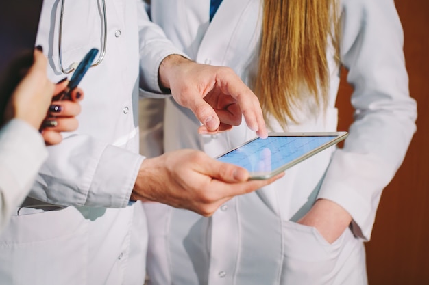 Artsen die het cardiogram van de patiënt op de tablet bespreken.