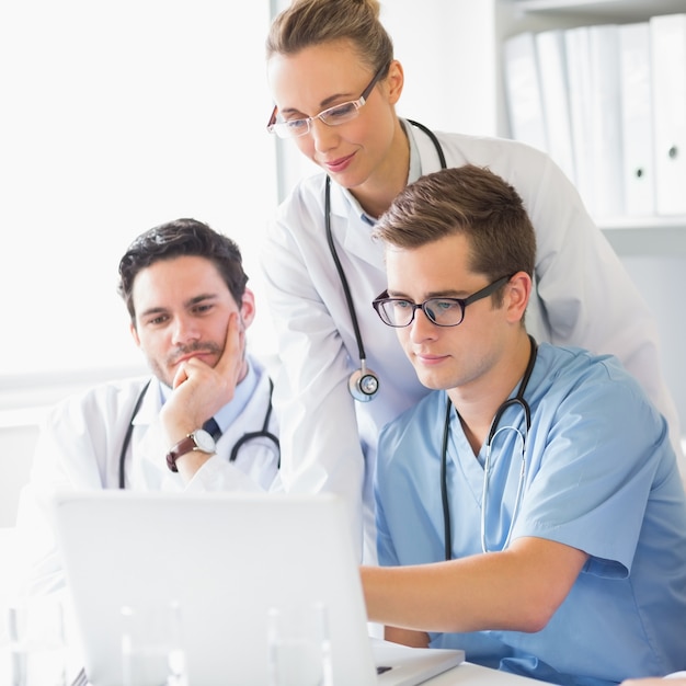 Artsen en verpleegster die aan laptop werken