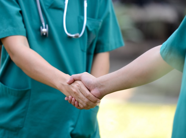 Artsen in een medisch team handdruk samen buiten op de achtergrond van het groene park (vrijwilliger)