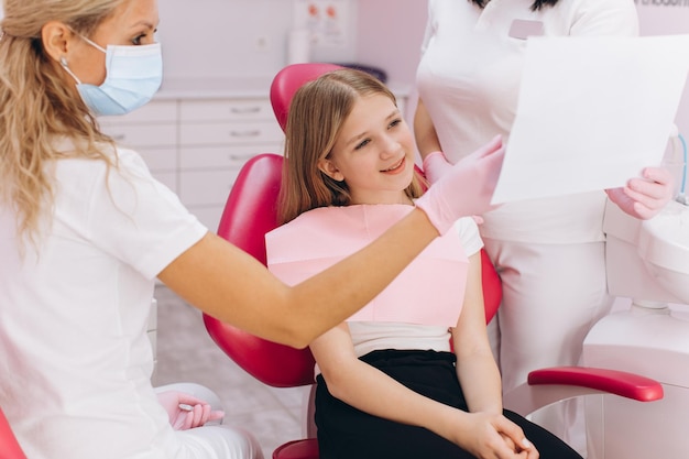 Artsen tonen een foto van tanden aan een tienermeisje in een tandheelkundige kliniek