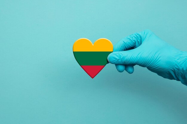 Artsenhand die chirurgische handschoen dragen die het hart van de vlag van Litouwen houden