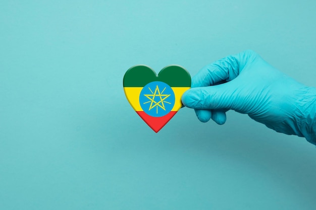 Artsenhand die chirurgische handschoen dragen die het vlaghart van Ethiopië houden