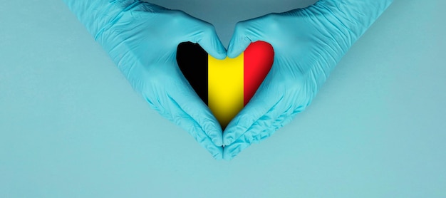 Artsenhanden die blauwe chirurgische handschoenen dragen en een vormsymbool horen met de vlag van belgië