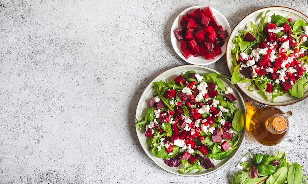 Insalata di barbabietola e formaggio di rucola con melograno e condimento su piastra su pietra grigia sfondo tavolo da cucina posto per testo vista dall'alto