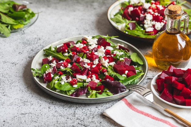 Insalata di barbabietola e formaggio di rucola con melograno e condimento su piastra su pietra grigia sfondo tavolo da cucina posto per testo vista dall'alto