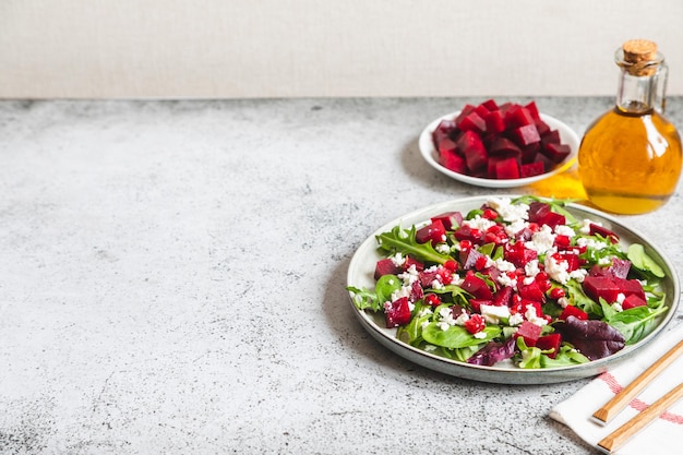 Arugula Beet and cheese salad with pomegranate and dressing on plate on grey stone kitchen table background place for text top view